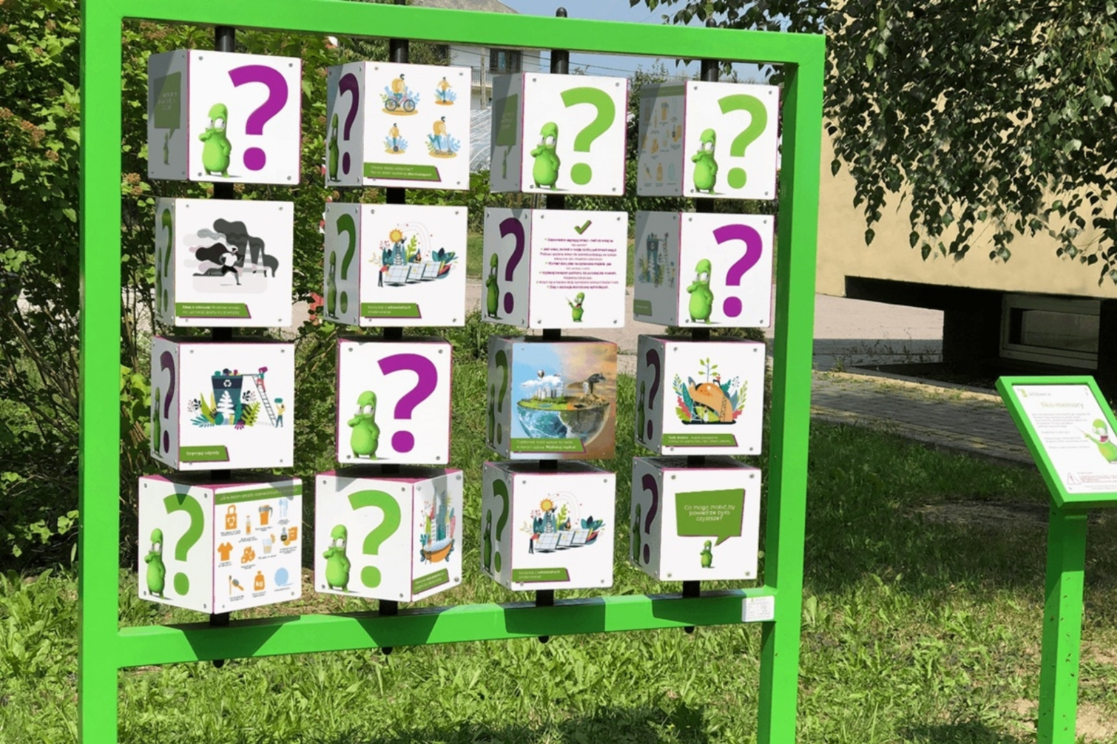 Smogo memory - urządzenie widziane pod kątem, latem na trawie, biało-zielone ścianki kostek w zielonej ramie