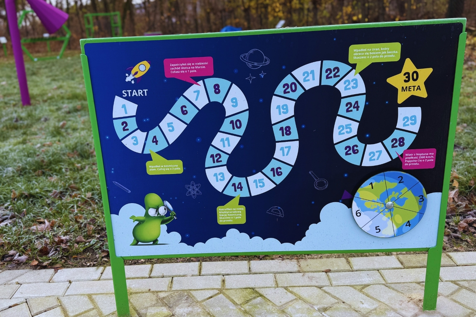 Tablica z&nbsp;grą Kosmos przy chodniku - plansza z&nbsp;30 polami, pięcioma dymkami i&nbsp;tarczą z&nbsp;globem na osi