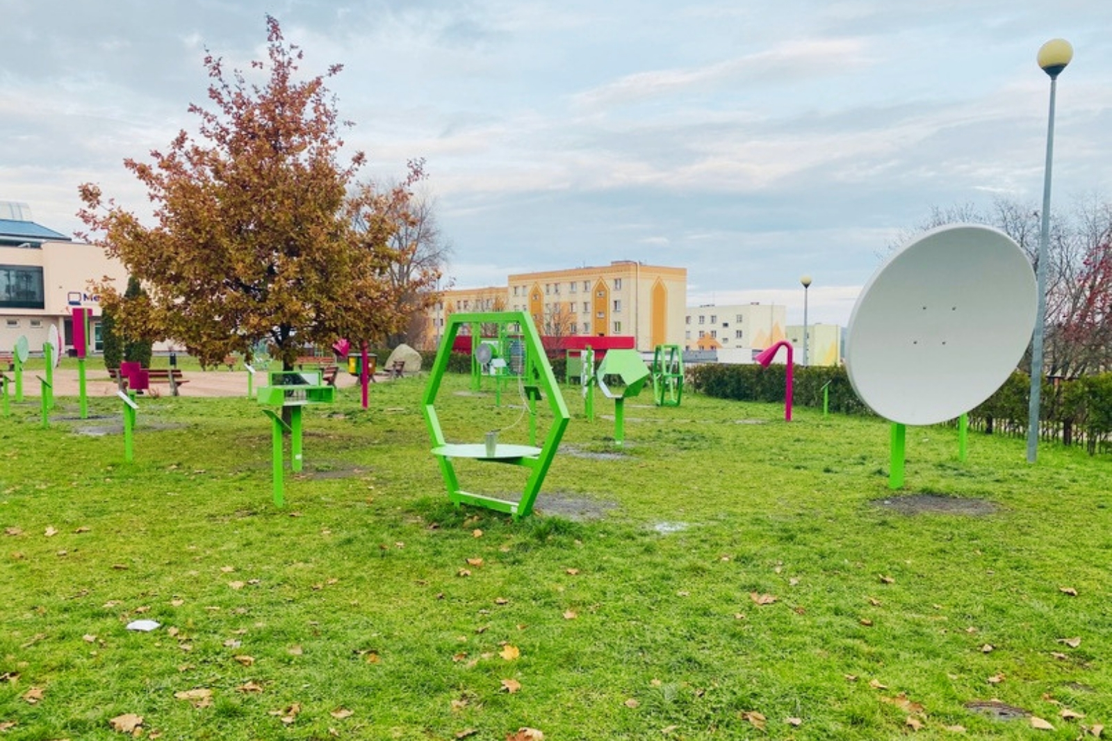 Telefon paraboliczny - dwa talerze paraboliczne po przeciwnych stronach placu zabaw, dzieci rozmawiają przez nie na odległość